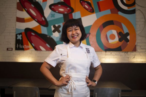 Chef Ji Hye Kim in a white apron in front of a painting in her restaurant
