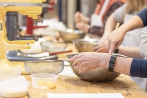 bowls, mixers, and ingredients on a table with hands