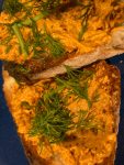 two pieces of toast with "Tunisian Pimento Cheese" topped with fresh herbs
