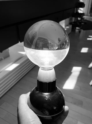 Energy. A black and white photo of a hand holding a turned on lamp in a room