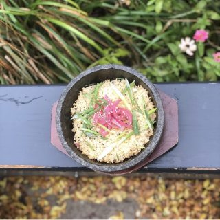 stone bowl bibimbob on a black wood railing with greenery on one side