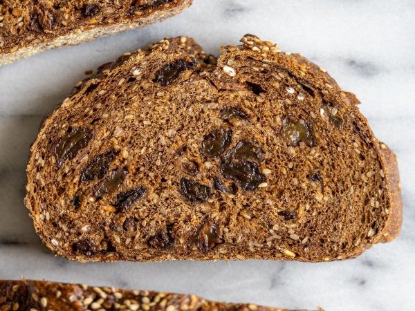 a slice of pumpernickel bread with  brown raisins in the middle with a crust around the slice of raisin bread